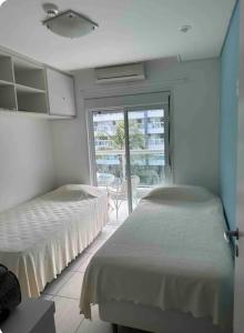 two beds in a bedroom with a view of a patio at ILHA DA MADEIRA Resort apto inteiro in Riviera de São Lourenço