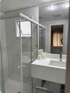 a bathroom with a glass shower and a sink at ILHA DA MADEIRA Resort apto inteiro in Riviera de São Lourenço