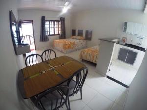 a room with a table and a kitchen with two beds at Suítes do Cid in Abraão