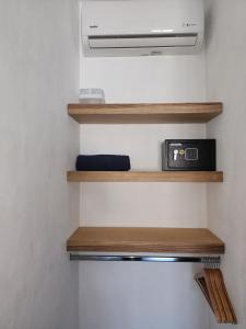 a room with wooden shelves and a microwave at Alma Del Bosque Hotel in Tortuguero