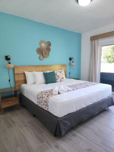 a bedroom with a large bed with blue walls at Alma Del Bosque Hotel in Tortuguero