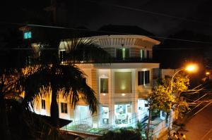 a white house at night with a palm tree at Daffodils Spice Court in Cochin