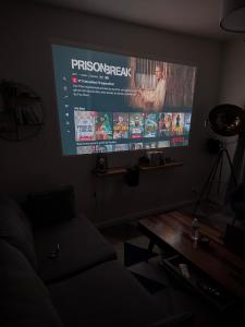a large screen in a room with a couch and a table at Le Loft de l'Artiste in Sèvres
