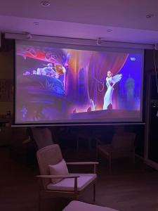 a large screen in a room with two chairs at LA MAISON DES VOSGES Nature & Pool in Senones