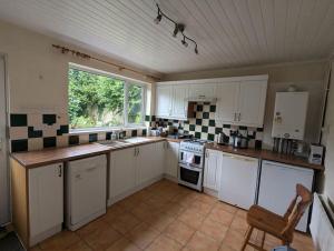 a large kitchen with white cabinets and a window at The Lodge - Built in the 1850s in Clydach