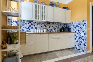 a kitchen with white cabinets and blue and white tiles at La casa di K i p l i n g "charme coloniale & storia" in Gorizia