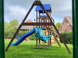 a playground with a slide and a swing at Moerenhof Schlafwagen "Pferdewiese" Xanten in Xanten