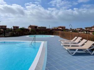 eine Reihe von Liegestühlen neben einem Swimmingpool in der Unterkunft THE PLACE - surf & soul in Majanicho