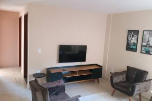 a living room with two chairs and a flat screen tv at Apartamento com varanda no centro de Aperibé in Aperibé