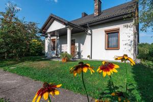 a house with yellow and orange flowers in the yard at Dworek na Zakręcie - noclegi Zator in Zator