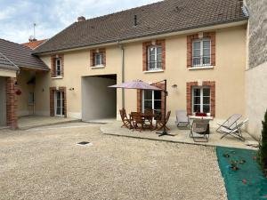 a house with a patio with a table and an umbrella at Maison Marguerite in Chouilly