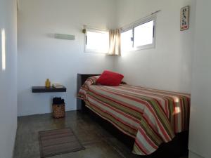 Un dormitorio con una cama con una almohada roja. en Acacias Apartamento D, en Punta del Diablo