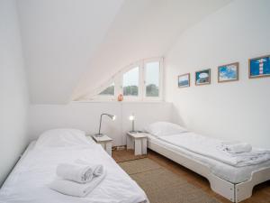 zwei Betten in einem weißen Zimmer mit Fenster in der Unterkunft Haus SEEGARTEN in Wustrow