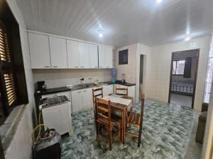 una cucina con mobili bianchi, tavolo e sedie di Pousada Paz de Mucuripe a Fortaleza