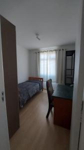 una camera da letto con un letto e una scrivania con una sedia di Leonis, Apto 32 a Curitiba