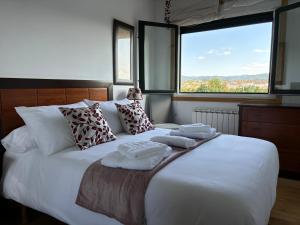 a bedroom with a large white bed with towels on it at El Rincón de Muxiña in Monforte de Lemos
