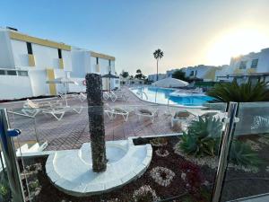 a resort with a pool and chairs and a palm tree at Bungalow Yaipe in Maspalomas