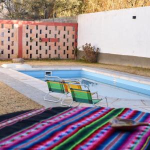 2 sillas de césped y una piscina con 2 sillas en Hostal amancay, en Cafayate