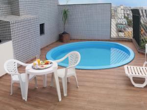 a patio with a table and chairs and a pool at Maxim Plaza Hotel in Juiz de Fora