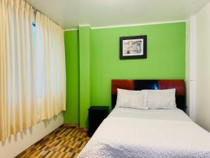 ein grünes Schlafzimmer mit einem Bett und einer grünen Wand in der Unterkunft Hotel Puerto Bayovar II in Mala