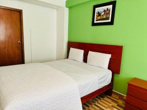 ein Schlafzimmer mit einem Bett und einer grünen Wand in der Unterkunft Hotel Puerto Bayovar II in Mala