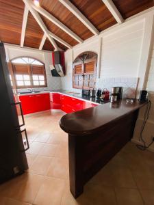 una cucina con armadi rossi e piano di lavoro nero di Villa Créole vue exceptionnelle Perle des Hauteurs a Le Carbet
