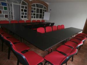 une salle de conférence avec une table noire et des chaises rouges dans l'établissement Penzion Mušlov, à Mikulov