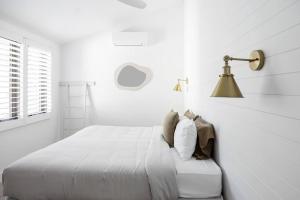 Dormitorio blanco con cama y lámpara en Otto Descola - Views, walk to Hastings St & beach, en Noosa Heads 20 fotos más