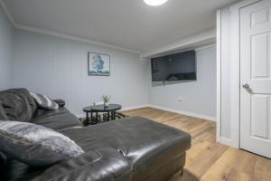 a living room with a leather couch and a table at Cute HighlandPark House in Calgary