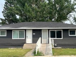 a gray house with a porch and a tree at Cute HighlandPark House in Calgary