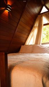 a bed in a wooden room with a window at Chalé Maloca in Cariry