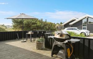 une moto garée sur une terrasse avec un parapluie dans l'établissement Awesome Home In Løkken With Kitchen, à Løkken