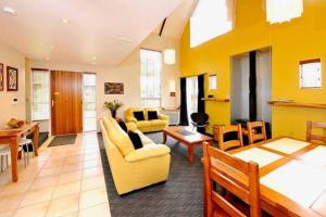 a living room with yellow furniture and a dining room at Gondwana Chalet perfect for all seasons in Ohakune
