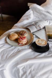 a plate of pastries and a cup of coffee on a bed at ARTOTEL Haniman Ubud in Ubud