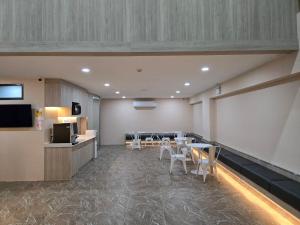 a room with tables and chairs and a kitchen at One Budget Hotel Nan Pha Sing โรงแรม วัน บัดเจท น่าน ผาสิงห์ in Nan