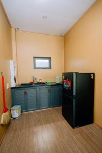 a kitchen with a black refrigerator and green cabinets at An Phú Villa in Cu Lao Thu