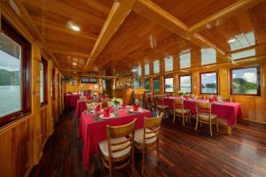 Un vagón comedor de un barco con mesas y sillas rojas. en Cat Ba Cruise, en Cat Ba