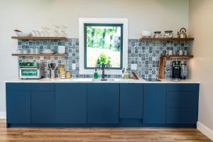 a kitchen with blue cabinets and a window at The Spruce Villa where luxury meets nature in Panther Creek +21 photos