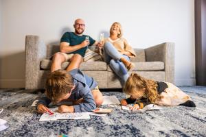 a family laying on the floor in a living room at voco Brisbane City Centre by IHG in Brisbane