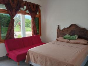 a bedroom with a red couch and a window at Valle de Toliman in San Lucas Tolimán