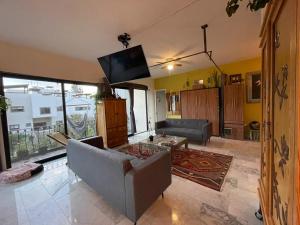 a living room with a couch and a flat screen tv at Casa Itzae La Antigua Dog Friendly in San Miguel de Allende
