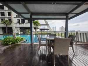 - une table et des chaises sur une terrasse avec piscine dans l'établissement 3706 Meridin Sovo Couple Legoland Netflix BySTAY, à Iskandar Puteri