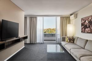 a living room with a couch and a flat screen tv at Holiday Inn Warwick Farm by IHG in Warwick Farm +70 photos