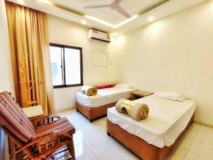a room with two beds and a chair in it at SEA VILLAS Salalah in Salalah +11 photos