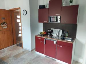 a small kitchen with red cabinets and a sink at Moderne Ferienwohnungen in Hitzacker in Hitzacker