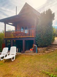 a house with two white chairs in front of it at Dom letniskowy ANTOLEK in Ryn +4 photos