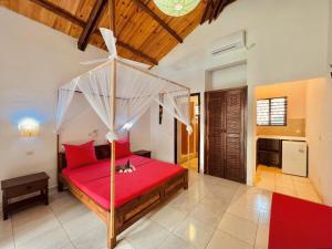 a bedroom with a red bed with a canopy at Résidence Kambana in Nosy Be +55 photos