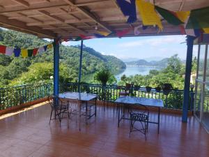 a balcony with tables and chairs and a view of a river at The Begnas sound healing center in Deorāli
