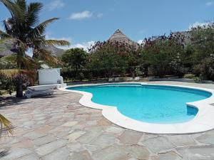 a swimming pool in a resort with a palm tree at Shira house in Watamu