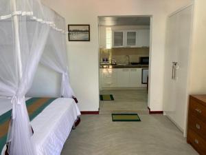 a bedroom with a bed with a canopy and a kitchen at Surf Side Komari in Arugam Bay